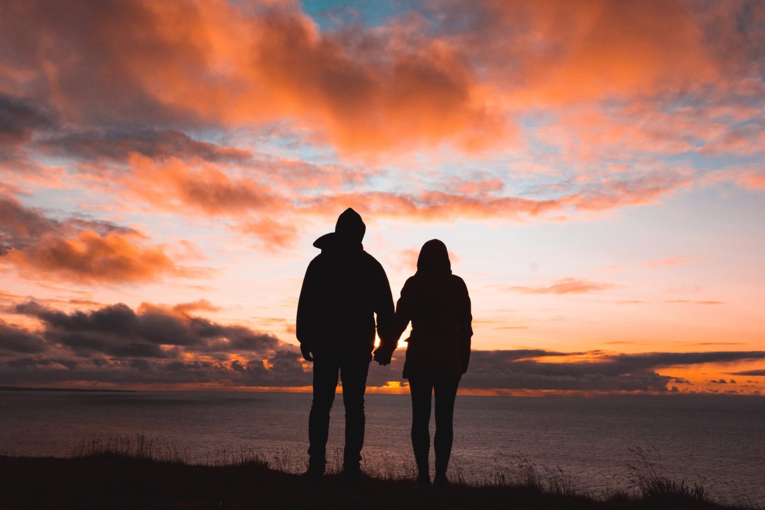 a couple of people standing on a beach at sunset